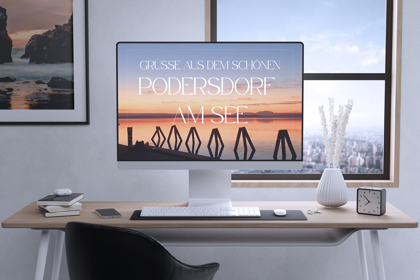 Ein moderner Arbeitsplatz verfügt über einen Computer mit der Anzeige „Grüße aus dem schönen Podersdorf am See“ und einem Bild eines Sonnenuntergangs am Seeufer. Ein Stuhl, eine Tastatur, eine Maus, eine Lampe, gerahmte Wandkunst und eine Uhr sind ebenfalls vorhanden. Ein Fenster bietet einen Blick auf eine Stadtlandschaft.